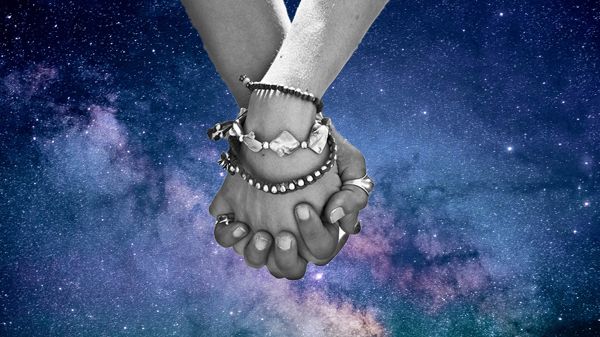 holding hands against background of starry sky