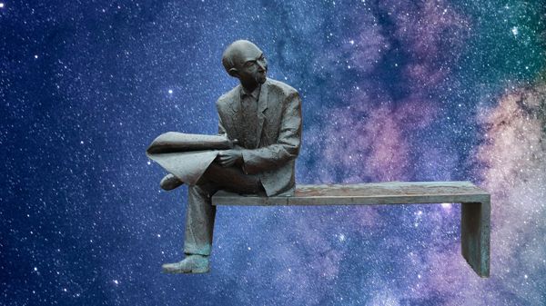 Statue of man reading newspaper on park bench with decorative starry background